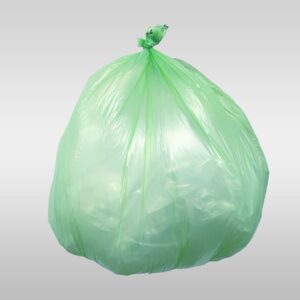 A green bag of garbage sitting on top of a white table.